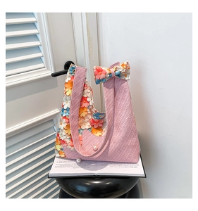 Detailed knit texture of pink floral tote with ribbon bow and pearl accents