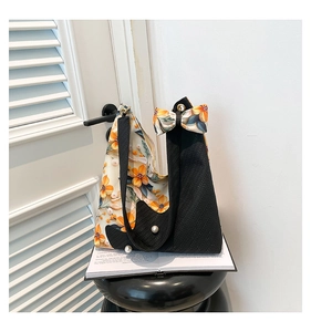 Detail of floral tote bag with bow accent and pearl charms on a stylish black stool