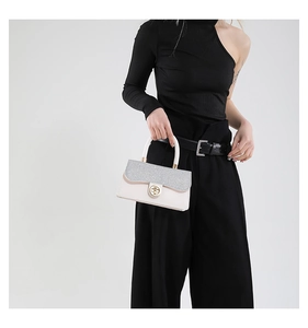 Detail of elegant small square bag with silver sequins, gold twist lock and round handle