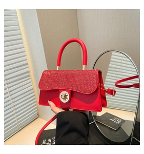 Detail of red sequined crossbody bag with gold round twist lock and leather handle