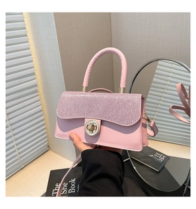 Detail of pink rhinestone crossbody bag with round metal rotary lock and curved handle