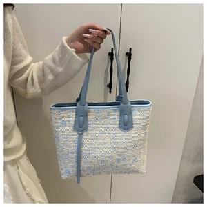 Close-up of woven tote bag with light blue leather handle and abstract spot patterns