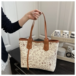 Detail of woven tote bag with cartoon bear print and brown leather shoulder straps