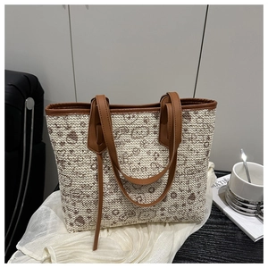 Detail of woven tote bag with cartoon bear pattern and brown leather handles on silk fabric