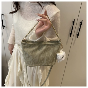 Detail view of light green pleated texture bag with chain handle and plush charm decor