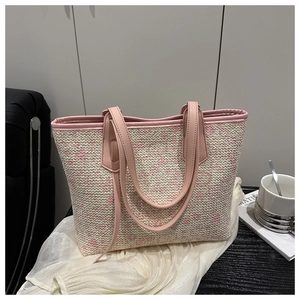 Detail of woven tote bag with pink leather handles and textured pink-white weave