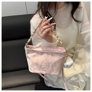 Detail of pink marble pattern bucket bag with gold chain strap and plush ball charm