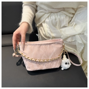 Close-up of pink pleated fabric tote bag with gold chain and white plush doll pendant