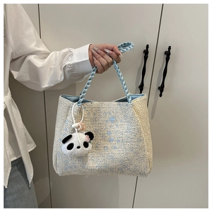 Détail d'un sac cabas tissé main en crème et bleu avec un adorable charm panda en peluche