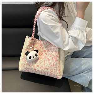 Détail du sac cabas tissé rose et beige avec charme de panda et bandoulières tressées