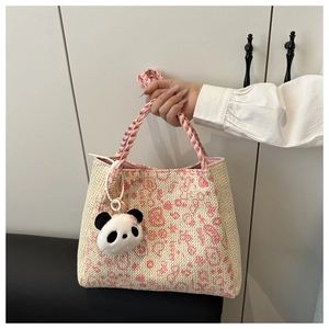 Détail d'un sac cabas tissé à la main crème avec motifs floraux roses et porte-clé panda