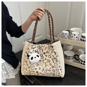 Détail du sac cabas en tricot léopard avec poignées en cuir et breloque panda