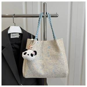 Détail d'un cabas en tricot avec motif floral bleu et porte-clés panda en peluche