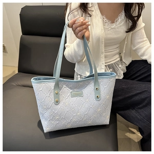 Detail of light blue tote bag with floral embroidery and branded leather patch