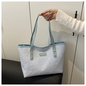 Detailed close-up of light blue quilted tote bag with delicate white bow patterns