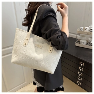 Close-up of white tote bag with textured pleated fabric and metallic rivet detail
