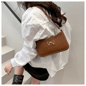 Detailed close-up of brown crocodile embossed leather bag with a golden bow buckle