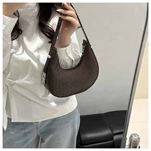 Detail of dark brown woven crescent underarm bag with silver zipper and retro texture