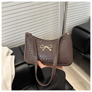 Close-up of brown crocodile texture underarm bag with golden bow metallic detail