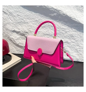 Close-up of contrast leather crossbody bag with pink stitching and gold round buckle