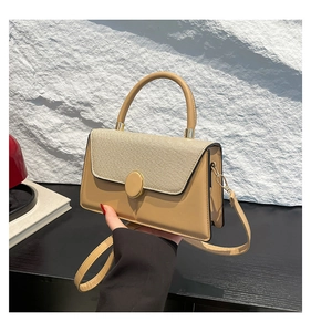 Detail of contrast stitching and woven texture on a minimalist khaki small square bag