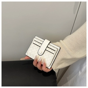 Close-up of white woven leather card holder with multiple slots and button strap