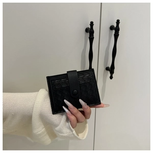 Detail of hand-held black woven leather card holder with secure snap button closure
