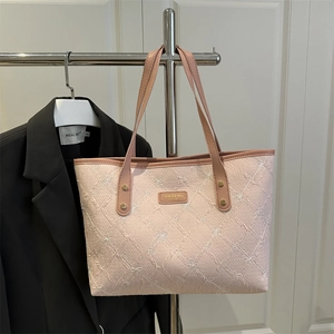 Pink textured floral tote bag with leather straps and metal logo on a minimalist rack