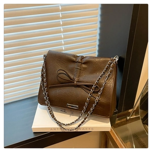 Detail view of a vintage brown faux leather handbag with bow and silver chain strap