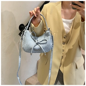 Detail of light blue crescent bag featuring a stylish bow and metallic brand logo