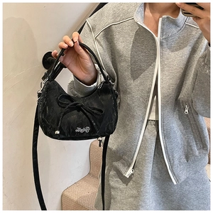 Detailed view of black crescent bow bag with metallic embroidery and polished texture