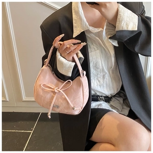 Detail view of pink glossy leather handbag with bow decoration and metal zipper