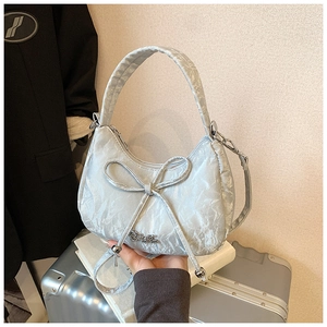 Detail of light blue pleated hobo bag with delicate bow and metallic zipper closure
