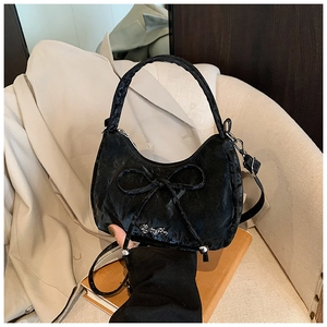 Close-up of black crossbody bag featuring a bow design and metallic logo detail