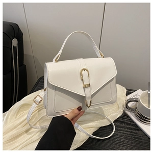 Détail du sac bandoulière blanc avec boucle en U dorée sur un décor minimaliste