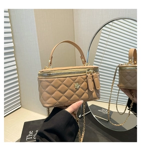 Detail of light brown quilted bag featuring a golden floral clasp and chain strap