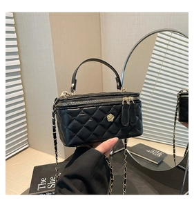 Close-up of black quilted mini handbag with gold camellia clasp and chain strap