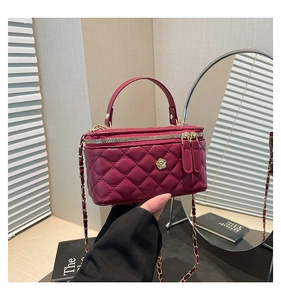 Detail of burgundy quilted leather crossbody bag with gold flower clasp and chain strap