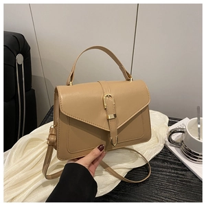 Gros plan sur un sac en cuir kaki avec boucle dorée sur une table en bois