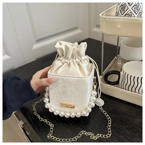 Detail van witte mini emmerstas met slangenprint, parelhandvat en gouden ketting