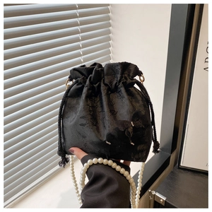 Detail of black drawstring bucket bag featuring butterfly jacquard and pearl handle