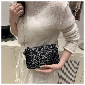 Gros plan sur le mini sac bandoulière léopard avec chaîne argentée porté par un mannequin