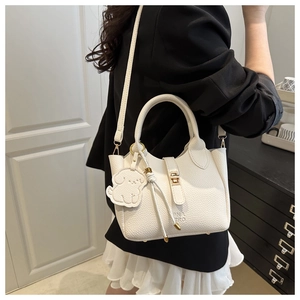 Gros plan du sac seau blanc avec texture en cuir, breloque chien et boucle métallique