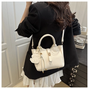 Gros plan d'un sac seau blanc en cuir grainé avec un charmant pendentif chien