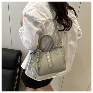 Détail du sac seau vert clair avec texture litchi, bouton métal et breloque chien