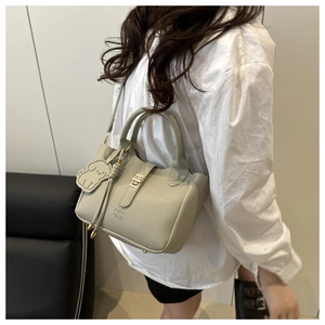 Détail d'un sac en cuir grainé avec fermoir doré et pendentif décoratif en forme de chien