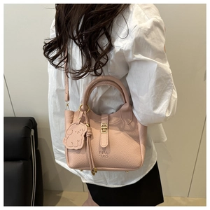 Détail du sac seau en cuir rose pâle avec ferrures dorées et breloque chien