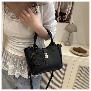 Détail du sac seau en cuir grainé noir avec fermoir métallique et breloque chien