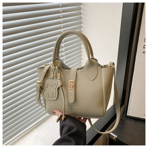 Détail du sac seau en cuir grainé avec fermoir métallique et pendentif chien décoratif