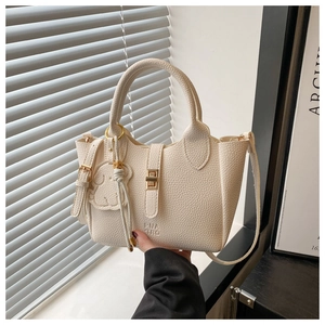 Gros plan d'un sac seau blanc crème avec pendentif ours et boucle métallique ronde